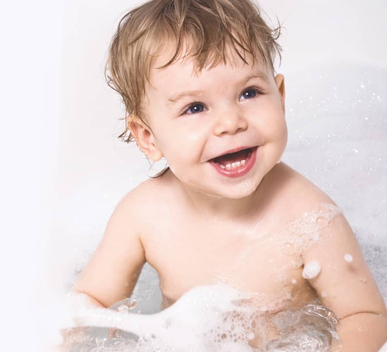 Photograph of a baby smiling in a bath
